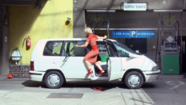 Eine Frau steigt in einem roten Kleid in einen weißen Van an einer BP-Tankstelle.