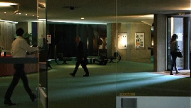 Ein Mann geht durch eine Drehtür, während andere Personen in einer Lobby zu sehen sind.