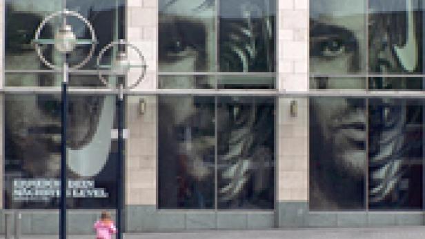 Ein Gebäude mit großen Fenstern, auf denen ein Nike-Werbeplakat mit dem Gesicht eines Sportlers zu sehen ist.