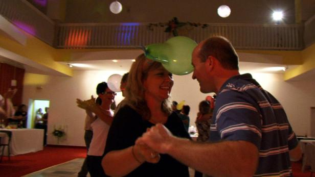 Ein Paar tanzt mit einem Ballon zwischen ihren Köpfen auf einer Party.