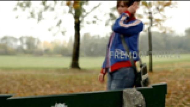 Eine junge Frau steht in einem Park und blickt in die Ferne.