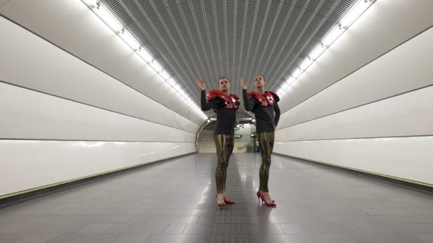 Zwei Personen in ungewöhnlicher Kleidung stehen in einer U-Bahn-Station.