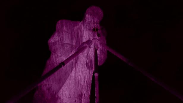 Eine violett beleuchtete Statue eines Mannes, der ein Blasinstrument spielt.