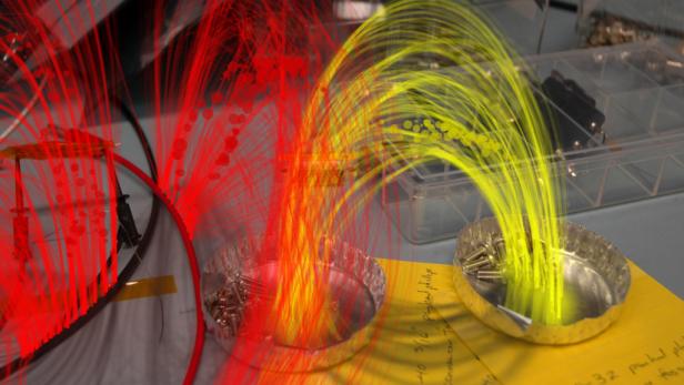 Zwei Schalen mit Schrauben, hervorgehoben durch rote und gelbe Lichteffekte.