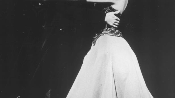 Ein Paar tanzt in eleganten Kostümen auf einer Bühne.