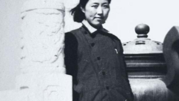 Eine junge Frau steht neben einer verzierten Steinsäule.