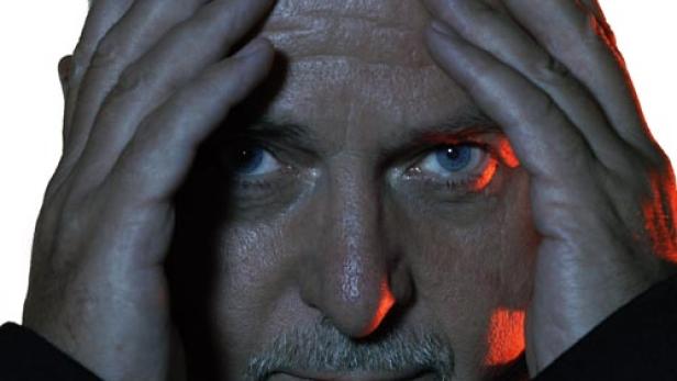 Porträt von Peter Gabriel mit den Händen an der Stirn.