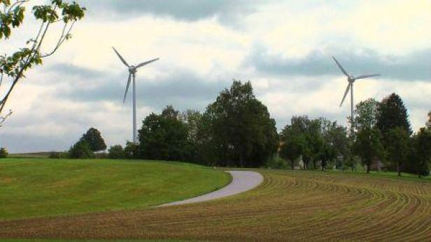 Zwei Windräder stehen auf einem Feldweg in ländlicher Umgebung.