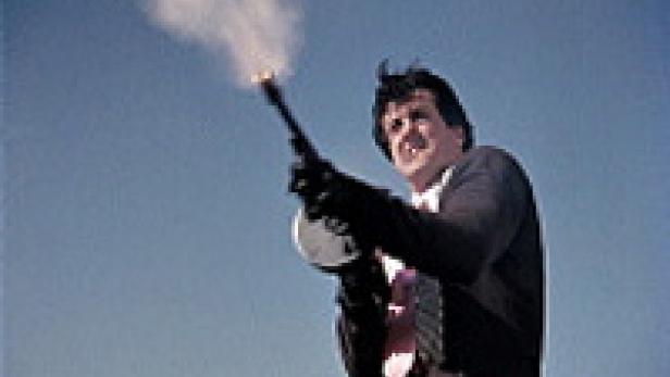 Sylvester Stallone feuert in einem Film mit einer Thompson-Maschinenpistole in den Himmel.