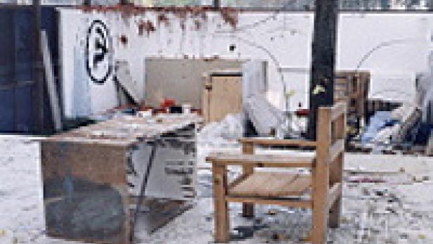 Ein zerstörter Raum mit einem Schreibtisch und einem Stuhl im Vordergrund.