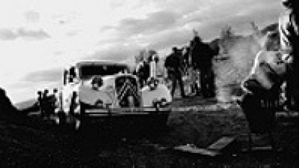 Ein Citroën Traction Avant steht auf einer Anhöhe, umringt von Menschen.