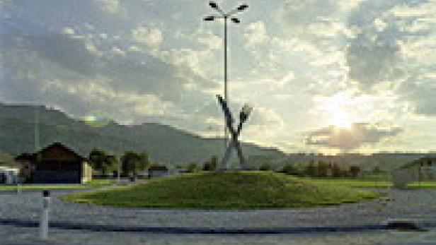 Ein Kreisverkehr mit einer Skulptur aus Gabeln und einem hohen Mast mit Lampen vor einer Bergkulisse.