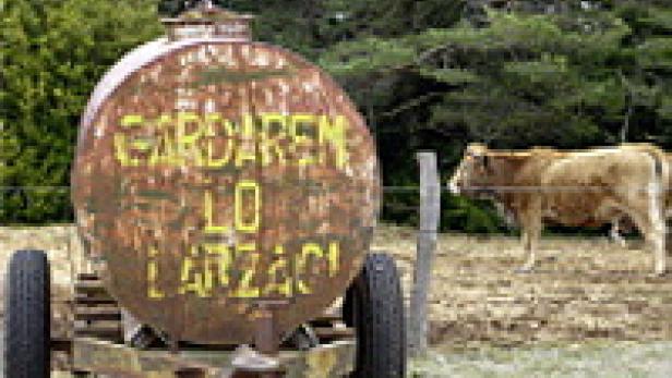 Ein rostiger Tankwagen mit der Aufschrift „Gardaren Lo Larzac“ steht auf einer Wiese.