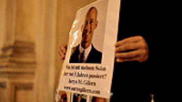 Eine Person hält ein Plakat mit dem Porträt von Aeya M. Gillers hoch.