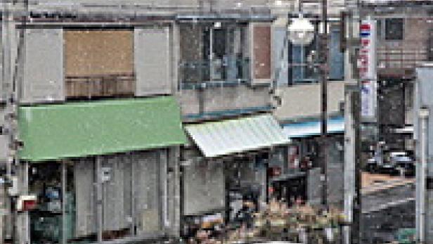 Eine verschneite Straße mit kleinen Geschäften in Japan.