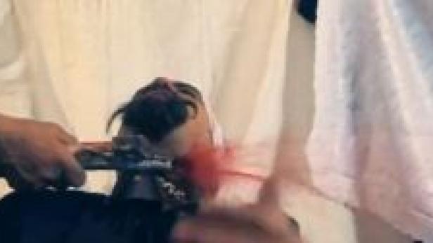 Ein Mann rasiert den Hals einer anderen Person mit einem Rasiermesser.