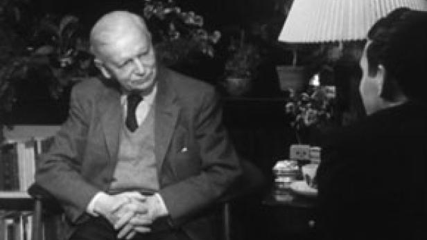 Ein älterer Mann sitzt in einem Sessel und spricht mit einer Person, die ihm gegenübersitzt.