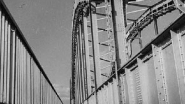 Eine Schwarzweißaufnahme einer Stahlbrücke mit vielen Nieten.