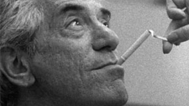 Leonard Bernstein raucht eine Zigarette.