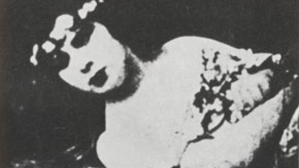 Eine Frau liegt mit geschlossenen Augen und Blumen im Haar da.