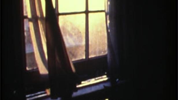 Ein Fenster mit wehenden Vorhängen lässt helles Sonnenlicht herein.
