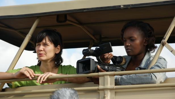 Zwei Frauen filmen aus einem offenen Geländewagen heraus.