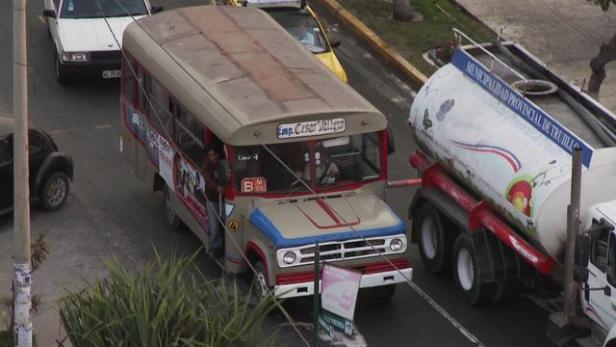 Ein beiger Bus der „Emp. Cesar Vallejo“ fährt auf einer Straße in Trujillo.