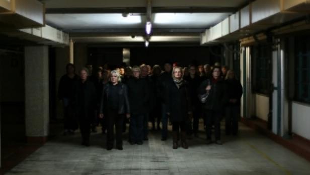 Eine Gruppe von Menschen steht in einem schlecht beleuchteten Gang.