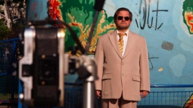 Ein Mann in einem Anzug steht vor einer Weltkarte, die mit Graffiti besprüht ist.