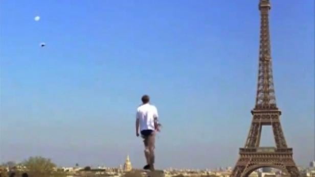 Ein Mann steht auf einem Sockel vor dem Eiffelturm in Paris.