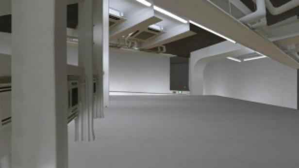 Ein leerer, weißer Raum mit Rohren und Lüftungsschächten an der Decke.