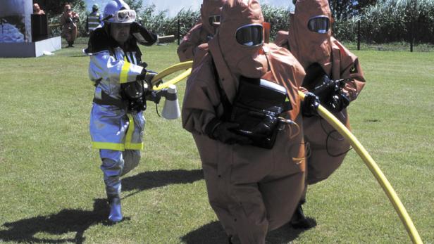 Eine Gruppe von Feuerwehrleuten in Schutzanzügen hält einen gelben Schlauch.