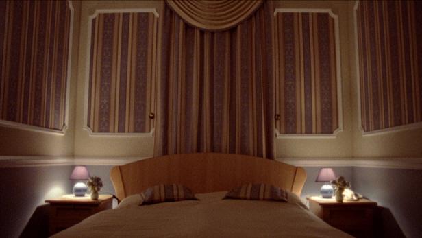 Ein Schlafzimmer mit einem Doppelbett und gestreiften Tapeten.