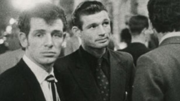 Zwei Männer in Anzügen stehen zusammen und schauen in die Ferne.