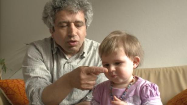 Ein Mann zeigt mit dem Finger auf die Nase eines kleinen Kindes.