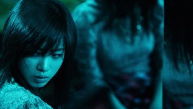 Eine junge Frau mit dunklen Haaren schaut nach unten.