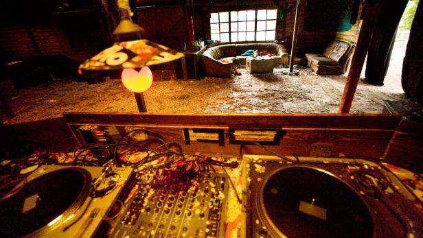 Ein DJ-Pult steht in einem Raum mit Sofas und einer ungewöhnlichen Dekoration.