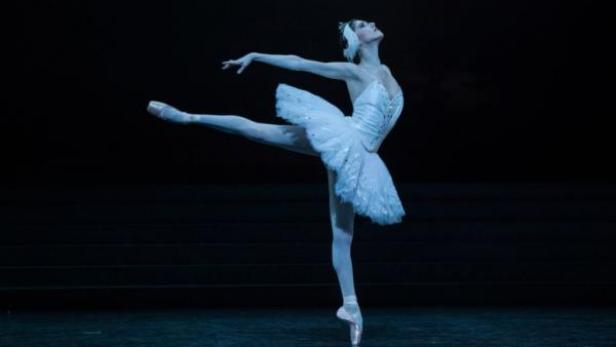 Eine Ballerina in einem weißen Tutu tanzt auf der Bühne.