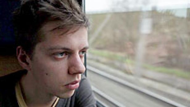 Ein junger Mann blickt aus dem Fenster eines Zuges.