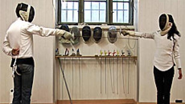 Zwei Fechter stehen sich mit Masken und Degen gegenüber.