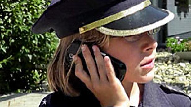 Ein Kind in Polizeiuniform telefoniert mit einem Smartphone.