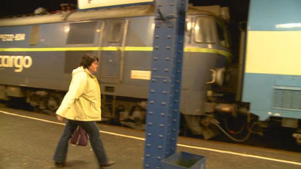 Eine Frau geht an einem Güterzug vorbei.