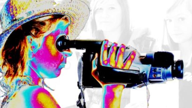 Eine Frau mit Hut filmt mit einer Videokamera.