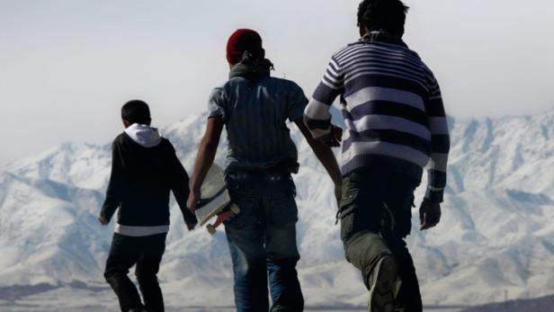 Das Filmplakat für „Skateistan“ zeigt drei Skateboarder mit Blick auf Kabul und die Berge.