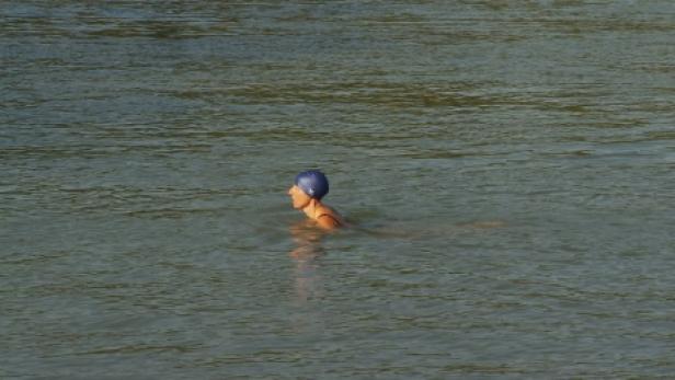 Eine Frau mit Badekappe schwimmt im Wasser.
