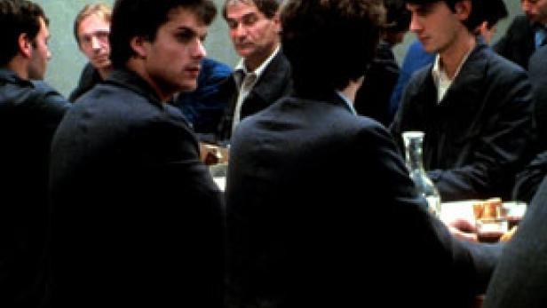 Mehrere Männer sitzen an einem Tisch und unterhalten sich.