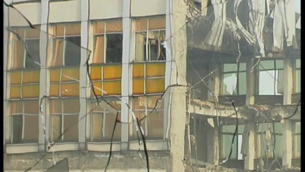 Ein zerstörtes Gebäude, gesehen durch eine zerbrochene Fensterscheibe.