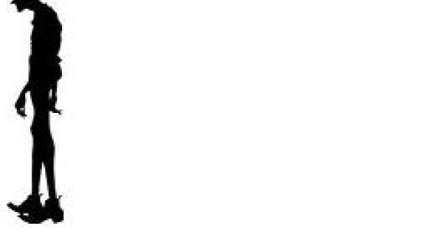 Die Silhouette eines Mannes mit Hut und Mantel steht da.