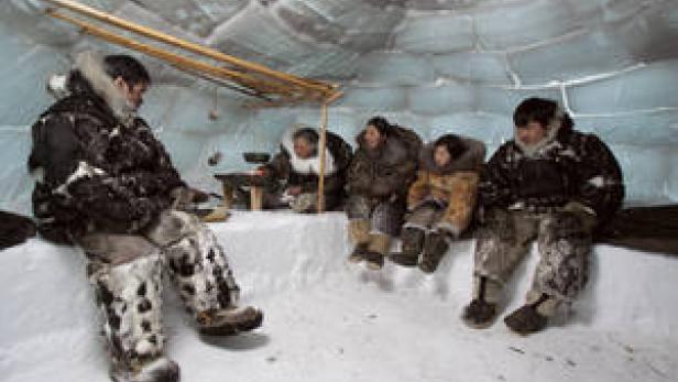 Eine Gruppe von Menschen sitzt in einem Iglu.