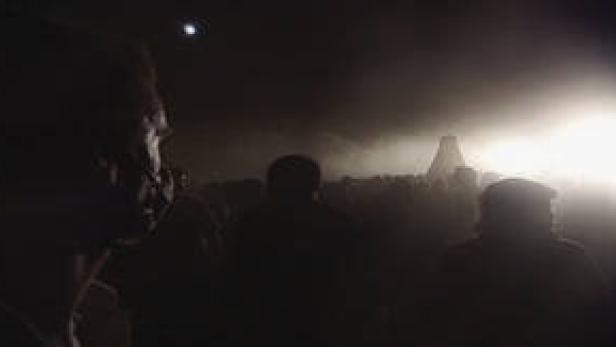 Eine Menschenmenge steht im Dunkeln vor einem hell erleuchteten Gebäude.